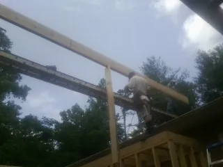Carpenter setting a ridge beam over a new addition frame — Ice Dam Removal by Roofing Brothers in Niota