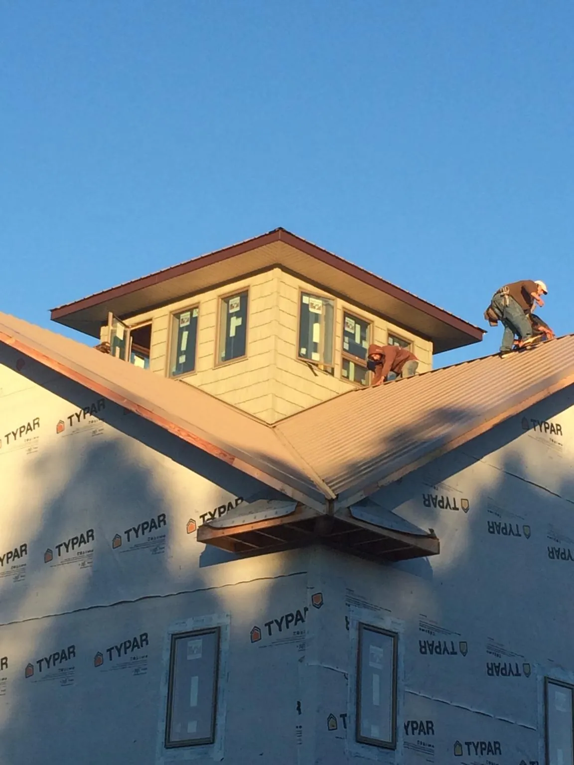 Roofers working around a rooftop cupola on a new metal roof at sunset — Roof Waterproofing in Niota by Roofing Brothers